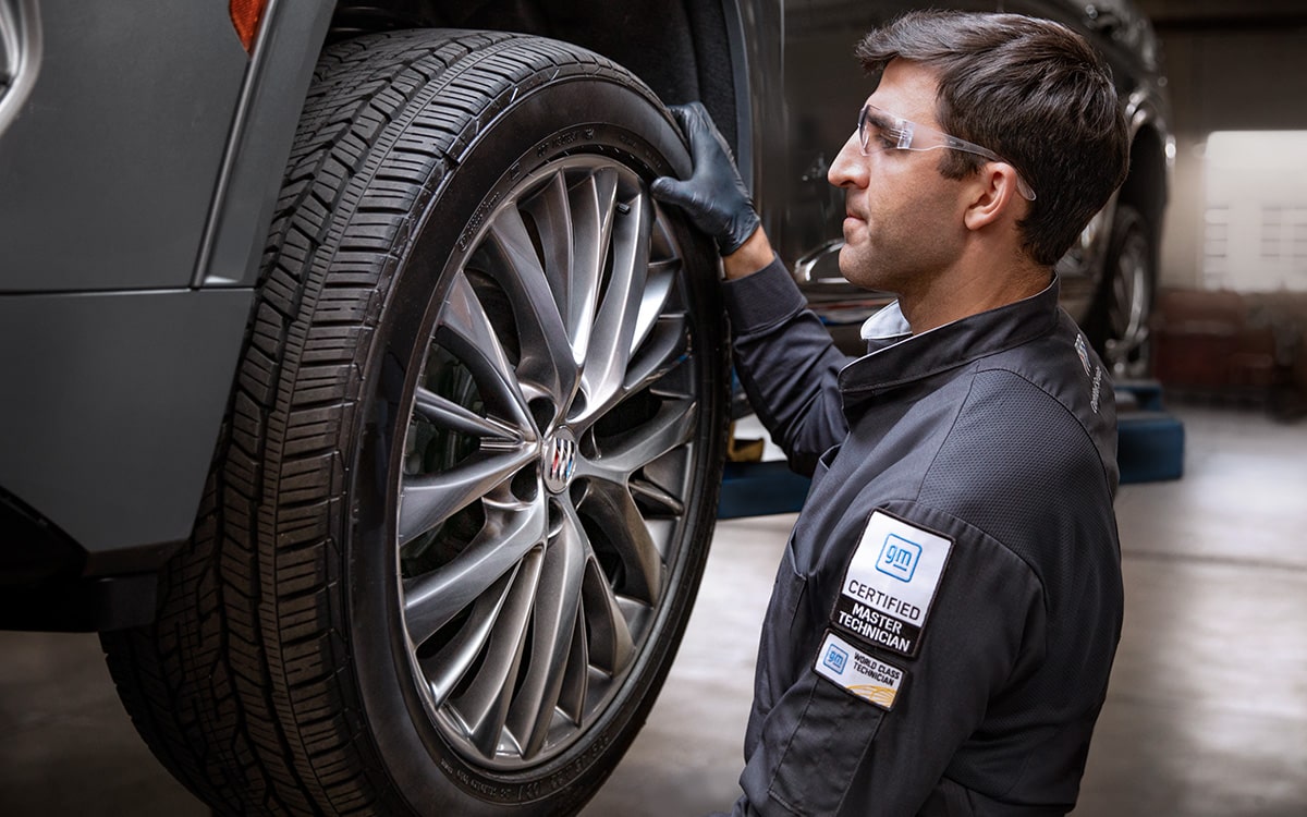 A Hand with Black Gloves Is Seen Working on One of the Wheels Of  A Chevrolet Vehicle