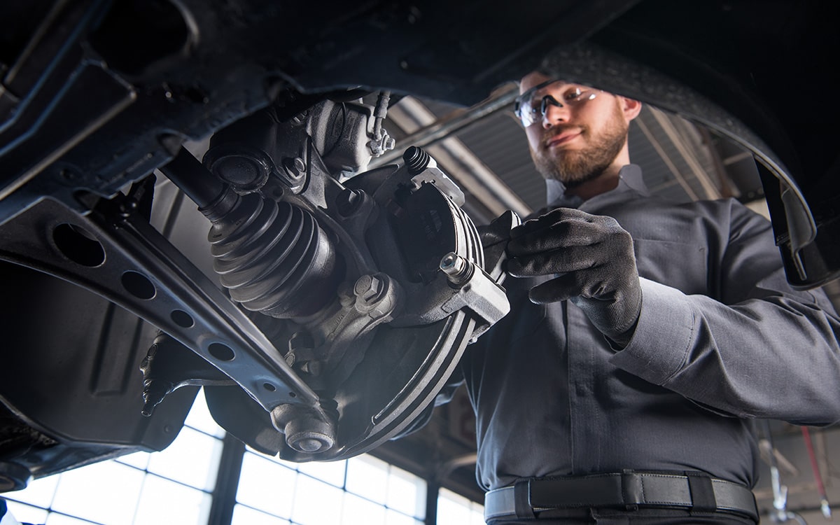 A Mechanic’s Hand Wearing Black Gloves Seen Placing the Metal Plate for the Wheel of a Chevrolet Vehicle