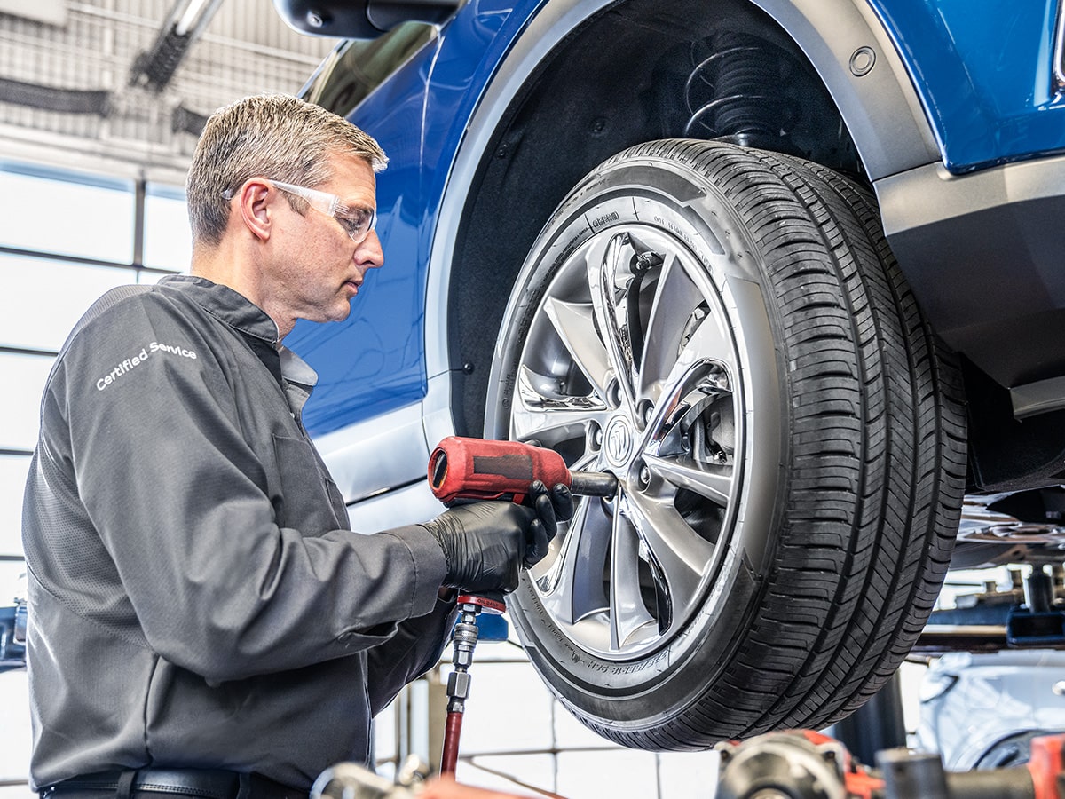 A Buick Certified Service Technician Tightening Bolts on a Vehicle's Wheels