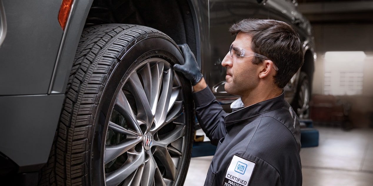 A Male Service Tech Installing a Tire on a Raised Vehicle