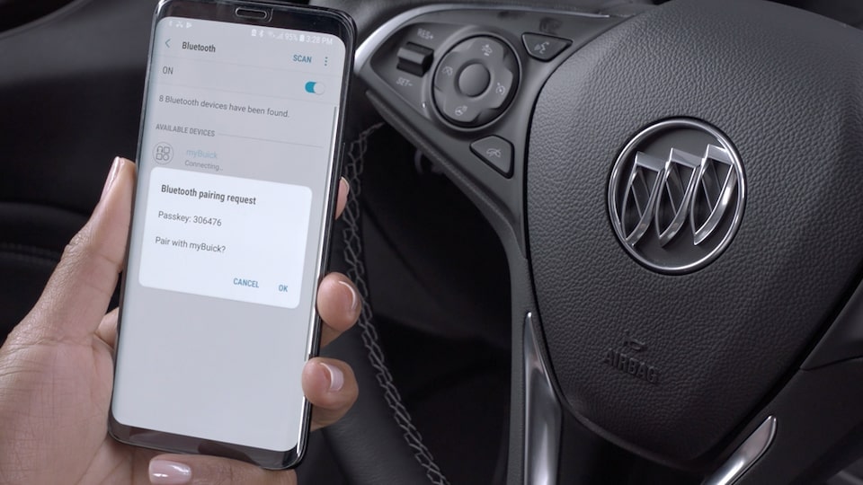 A Buick Vehicle Driver Holding Up His Phone To Connect to the MyBuick App