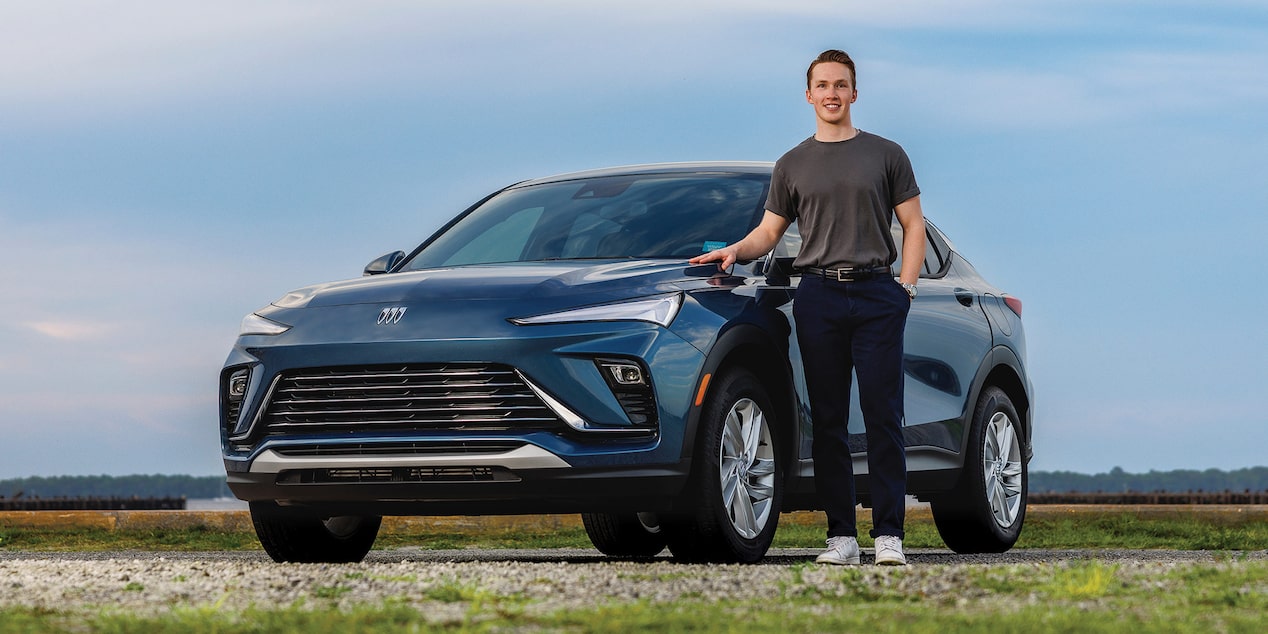 A Man Standing Next to a Parked Buick Envista