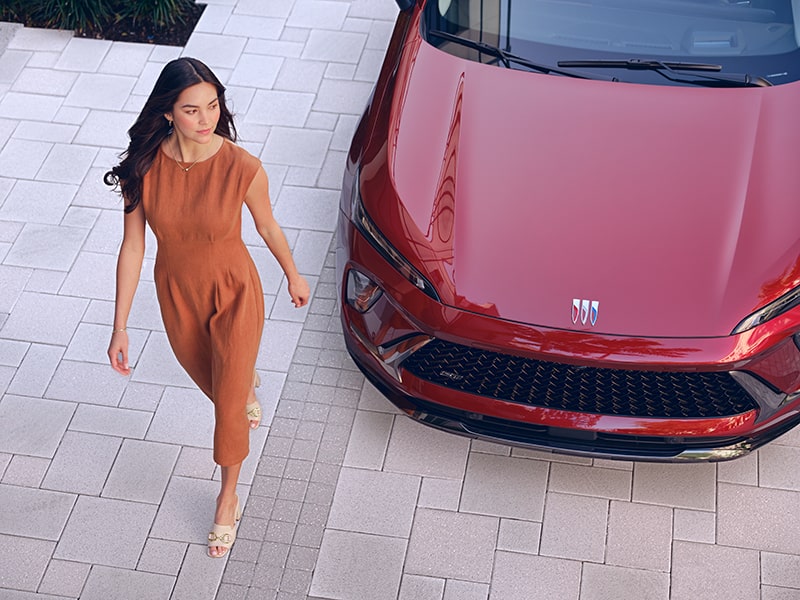 Women walking next to a parked red 2024 Buick Envision