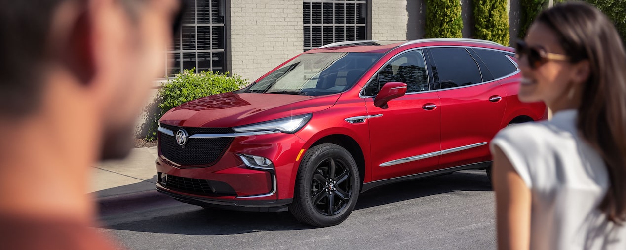 Two People Walking Toward Their Red Buick Enclave