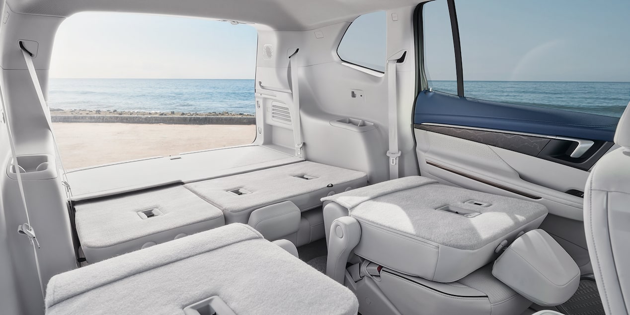 The Rear Passenger Seats Are Folded Down with the Trunk Hood Open Leading to a Beach Outside